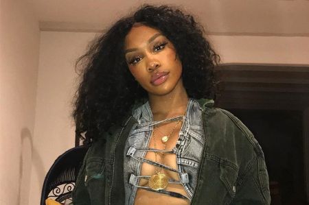 sza with minimal makeup open curly hair, wearing a jacket 